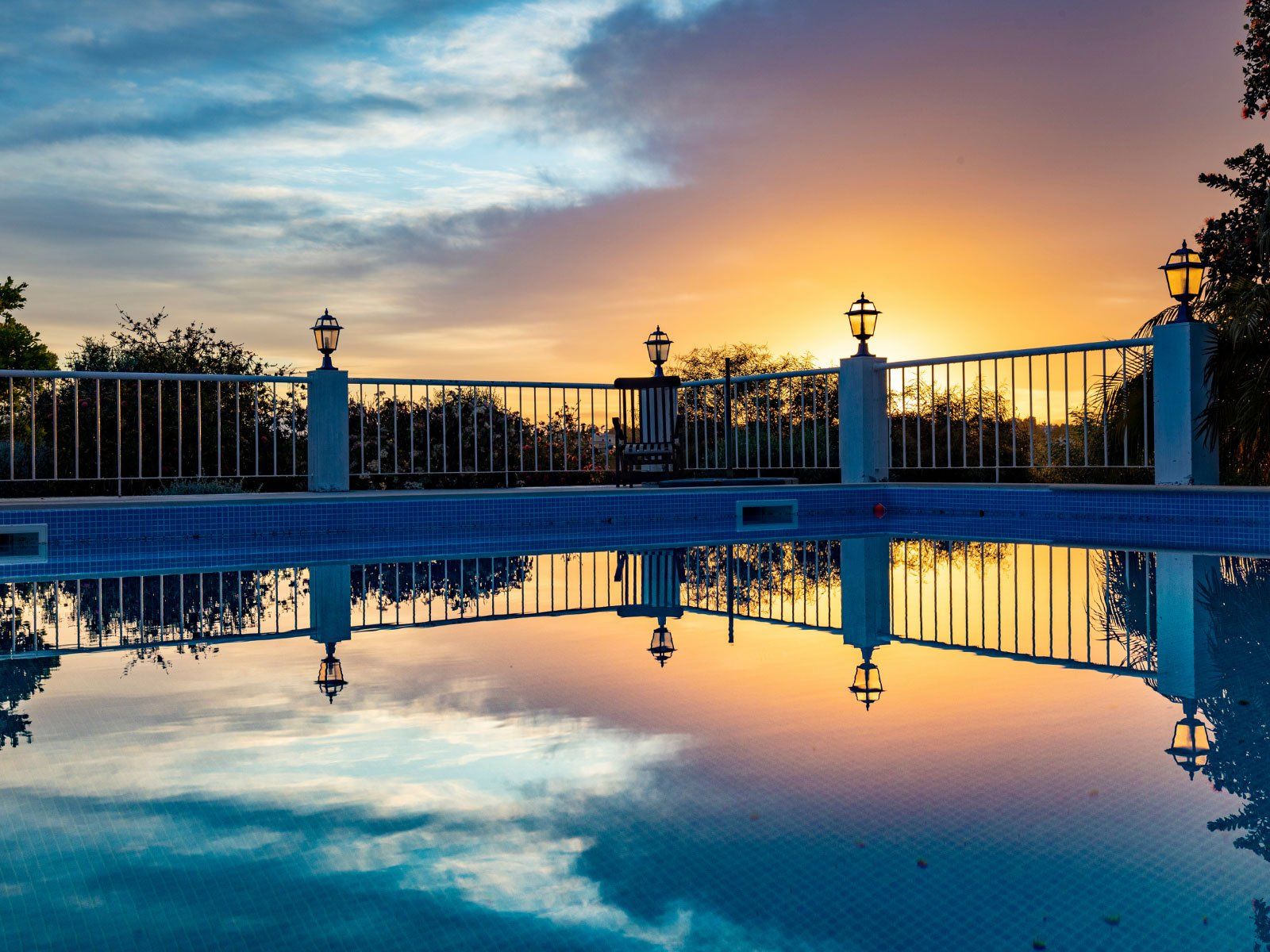 Swimming pool with a white pool safety fence at sunset